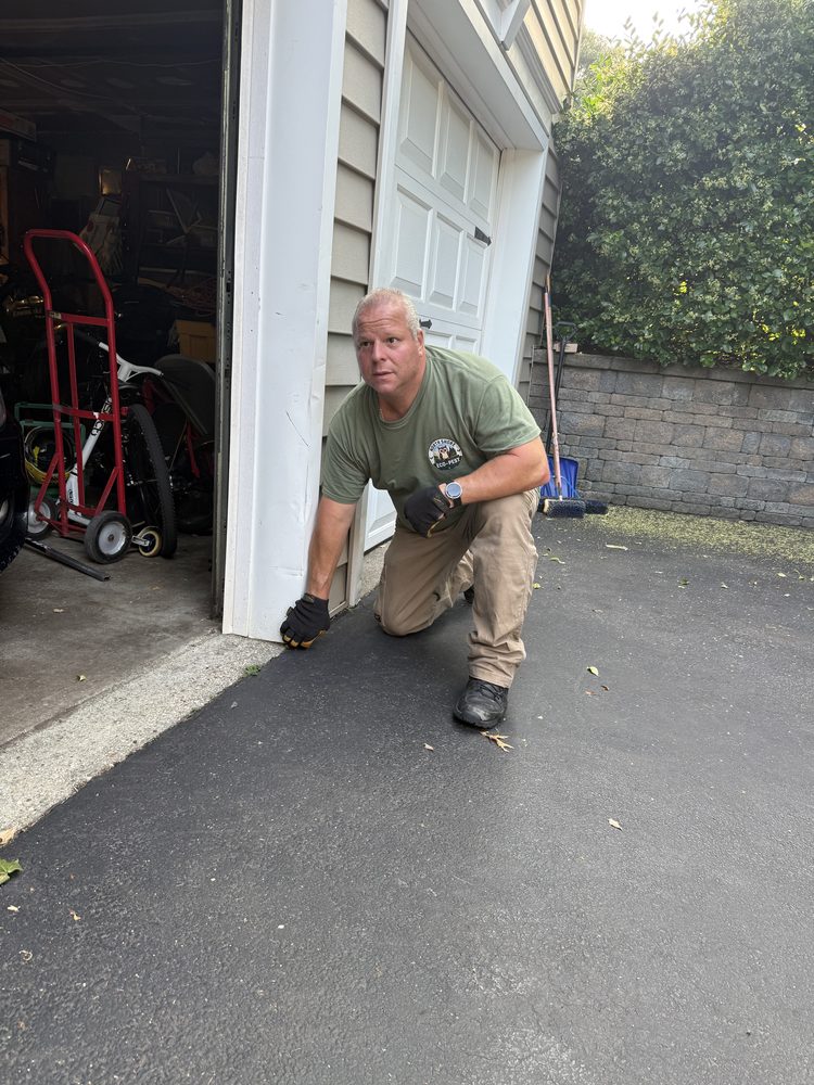 Steve Rocco Tardalo inspecting a garage door threshold for rodent entry points